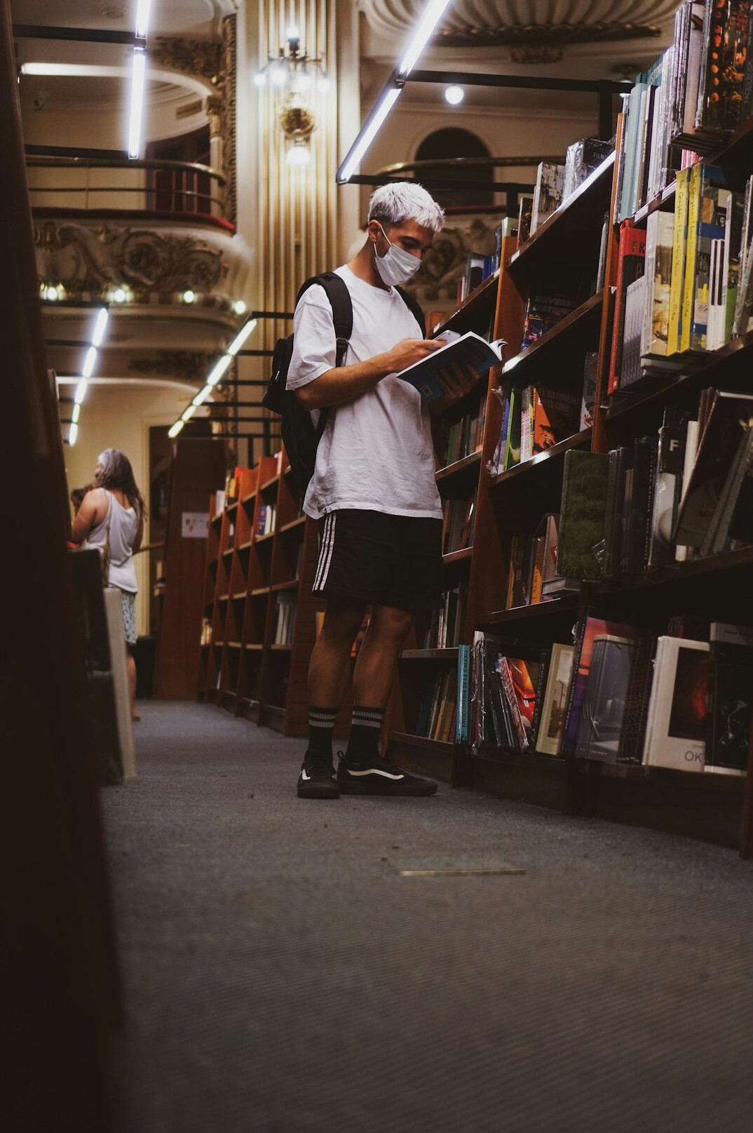 Older volunteer reading a book aloud to children in a library