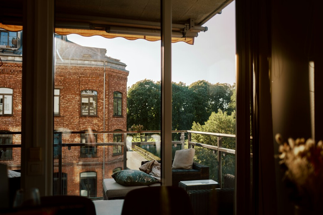 Older man reading a tablet on a sunny balcony with a cup of coffee